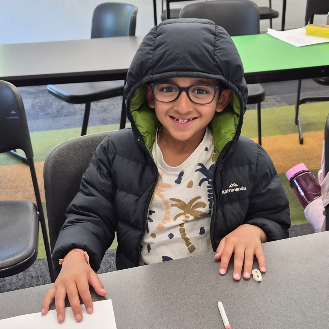 Smiling student sitting at a desk at NRICH Learning